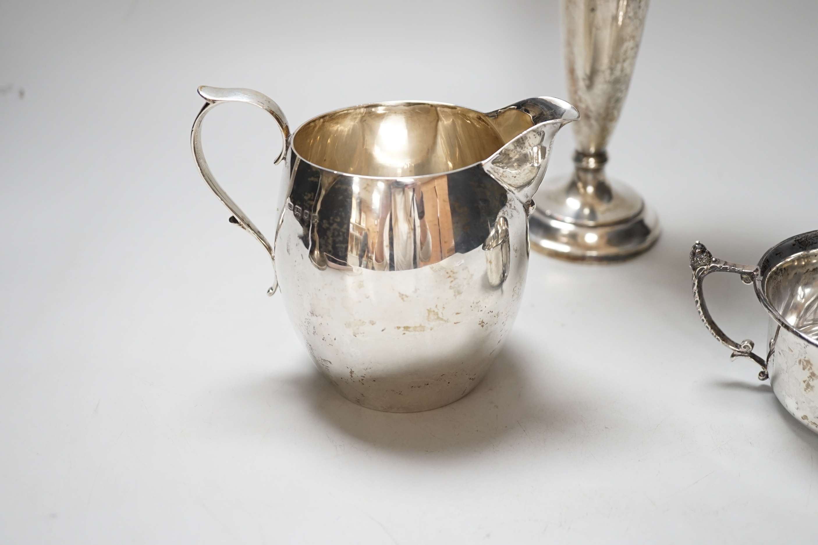 A George V silver cream jug, London 1926, 216 grams, a sugar bowl, Birmingham 1924, 107 grams and a spill vase with loaded base, Birmingham 1919, 20.5cm